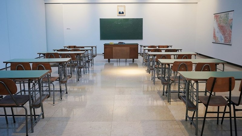 A classroom with a board, tables, and chairs for students to sit in.