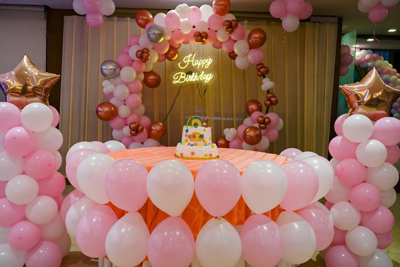 A room decorated for a birthday party with pink and white balloons-