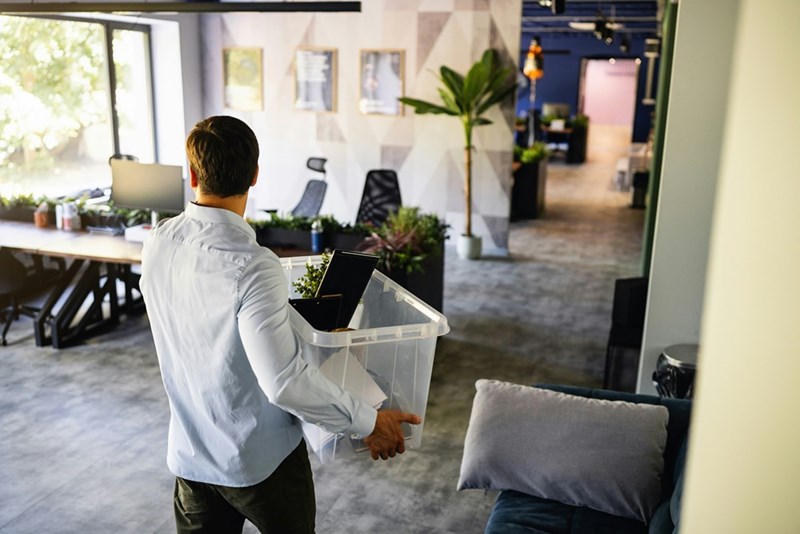 A man carries his belongings out of the office