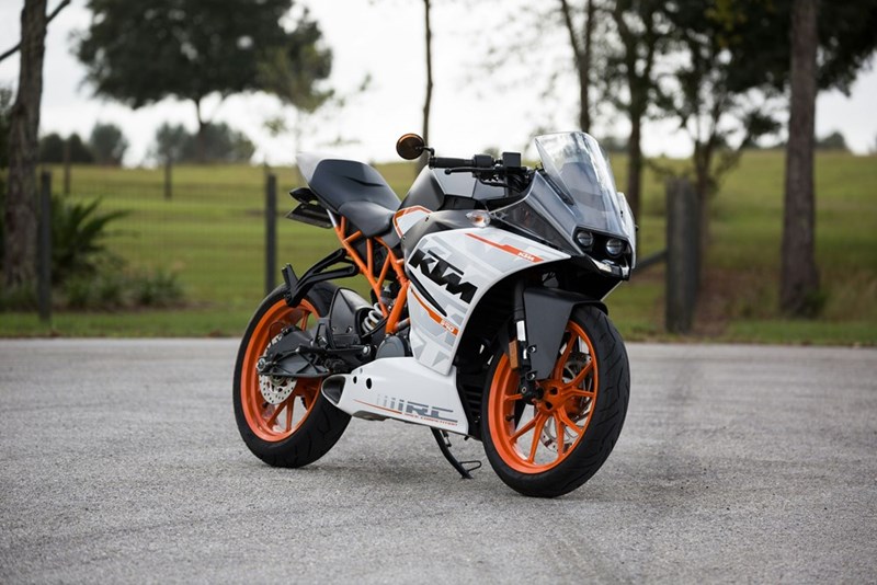 A white and orange motorcycle parked outside of an apartment complex.