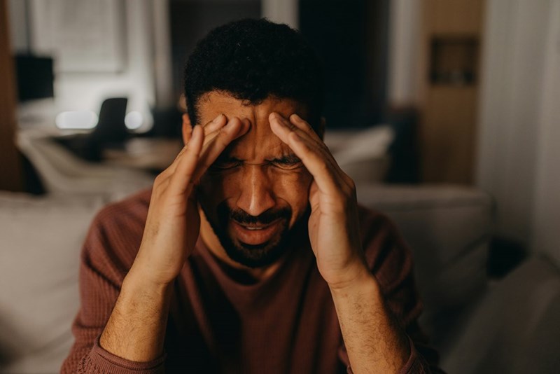 An angry man holding his head after realizing a neighbor sold his motorcycle when he was away.