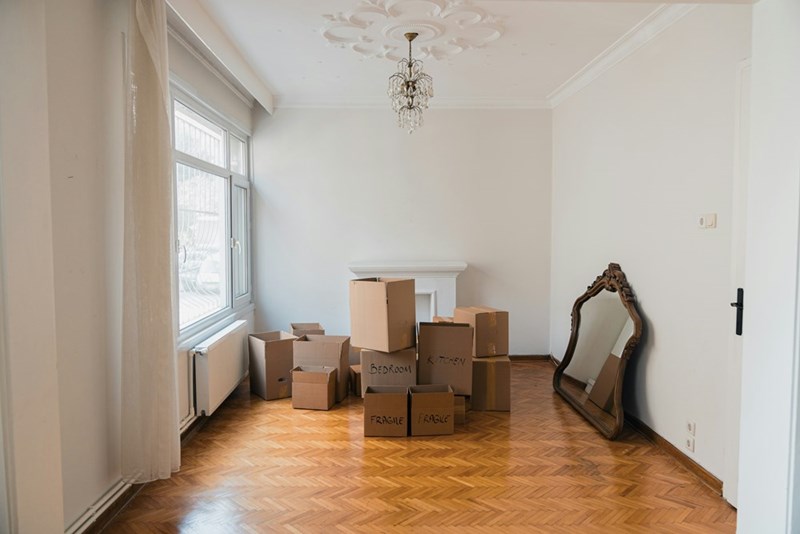An empty room full of boxes, as a couple just bought the house and is moving in.