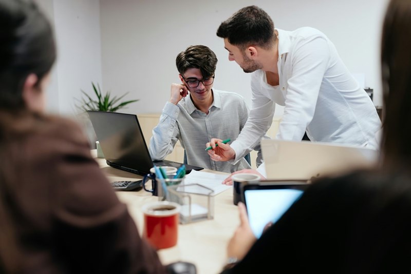 a group of coworkers discussing paperwork around a table in an office