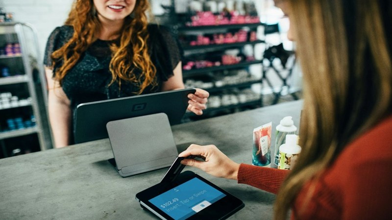 A cashier charging the customer, and the customer paying with a credit card. Image for illustrative purposes.
