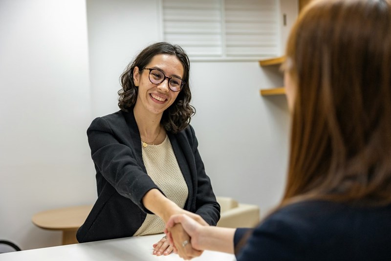 Two women holding hands as they close a deal. Photo is a representation of scenes.