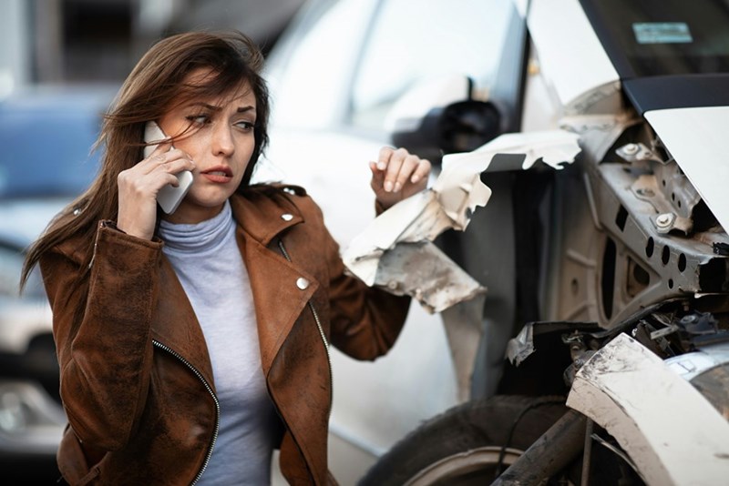 A woman next to her broken-down car.