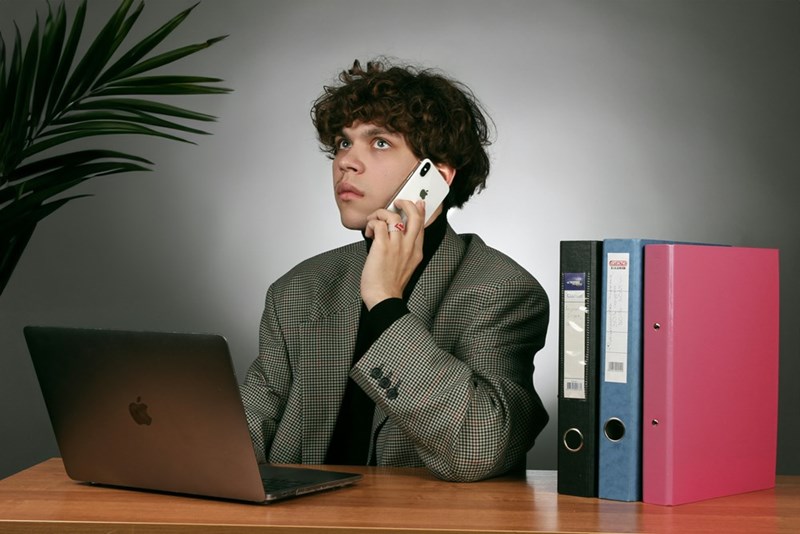 An employee sits behind a desk holding a phone to his ears