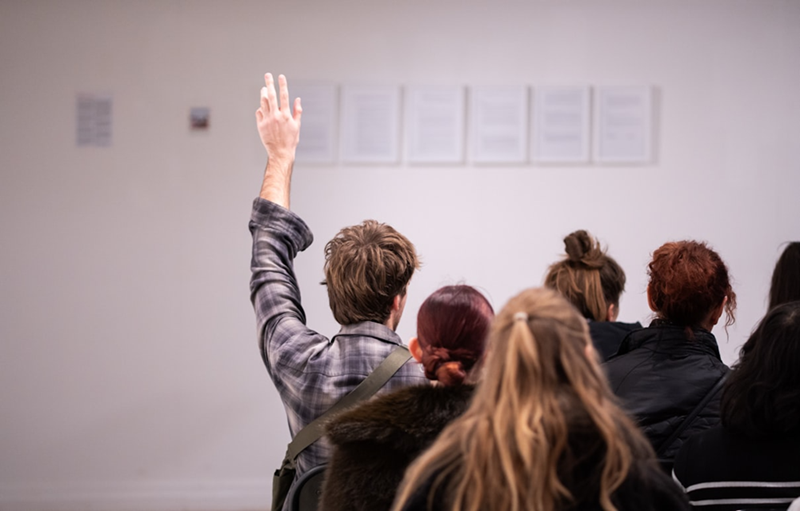A man holds up his hand to bid during an auction.