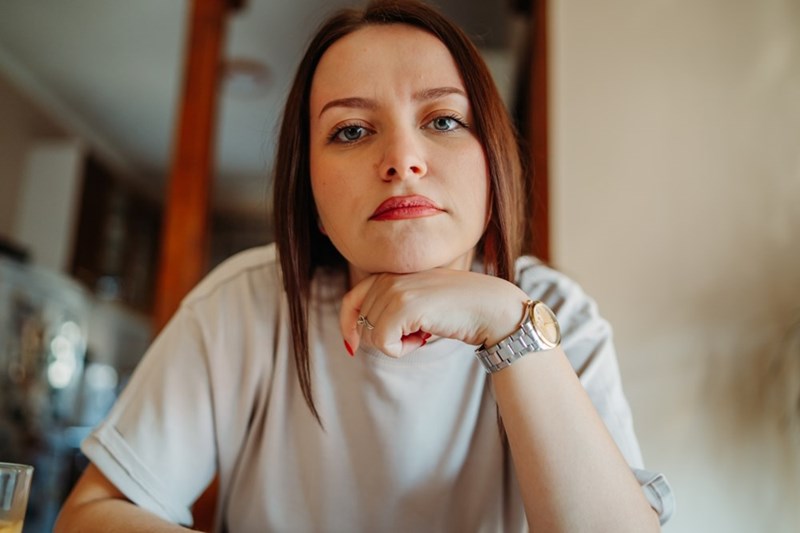 Woman resting her chin on her hand looking straight ahead with a serious unimpressed look