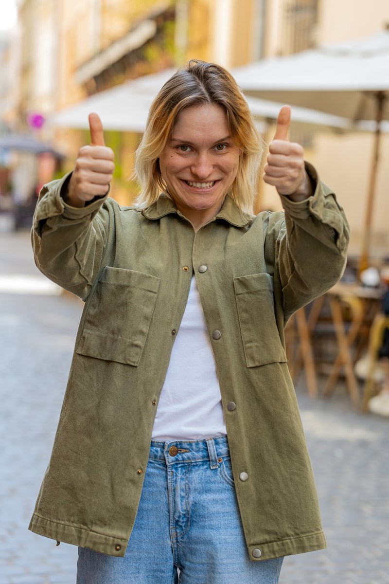 woman smiling giving thumbs up with both hand like she's happy with the result of something