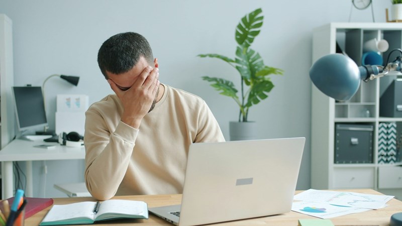 Frustrated office worker sitting at his laptop after realizing his company never considered him for the management role he hoped to earn.