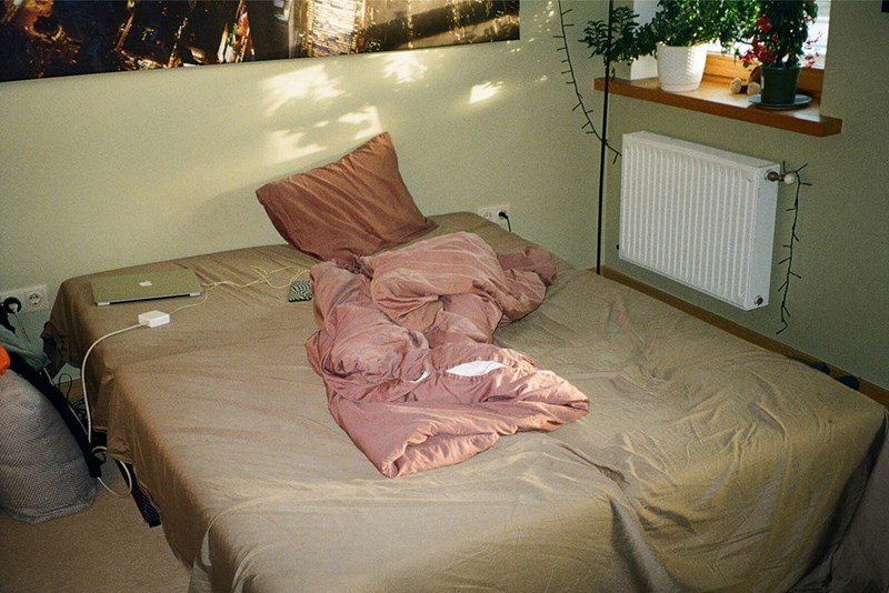 A bed in an apartment with crumpled up sheets and mess