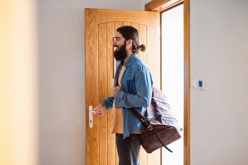 A man opens the door to his apartment and looks ahead of him