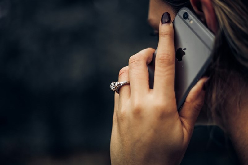 A woman talking over the phone with the coworker. Model portrayal.