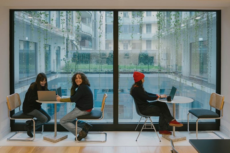 Workers work in a cafeteria due to there being no room in the office