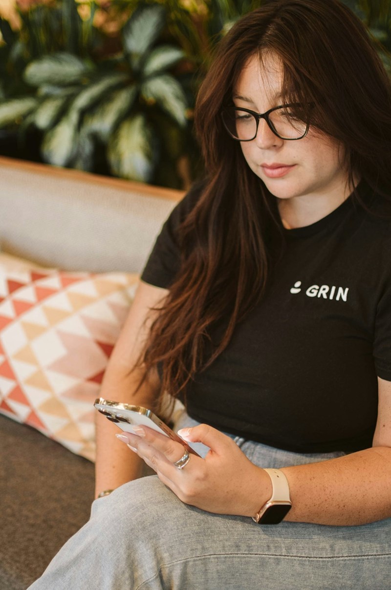 A young employee looks at her phone while sitting on a bench at work