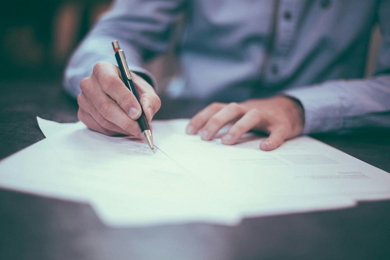 The father signs the will that makes only one sibling get the inheritance. Image for illustrative purposes.