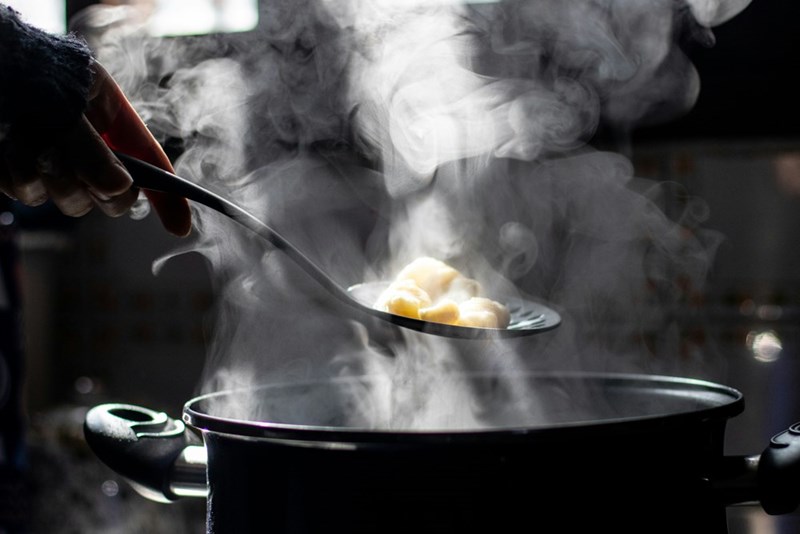 Someone spoons pasta out of boiling water