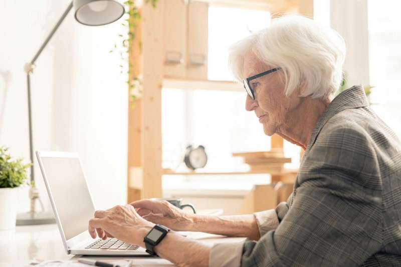Old lady wearing glasses is working on the computer for the same factory.