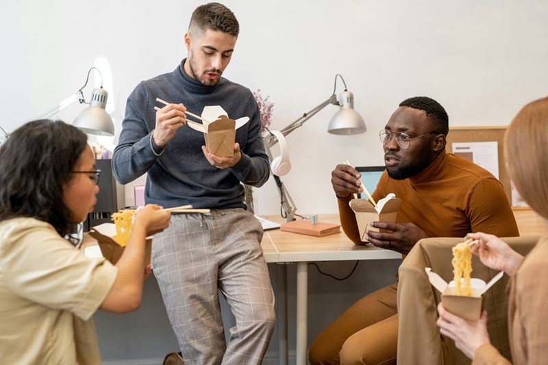 Coworkers eating lunch together during a break from their workday at the office.