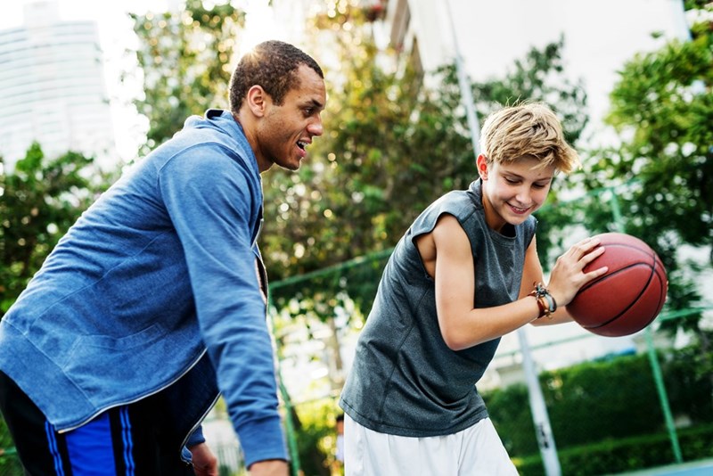 Coach playing basketball with young player