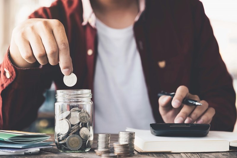 Man putting money in a glass jar