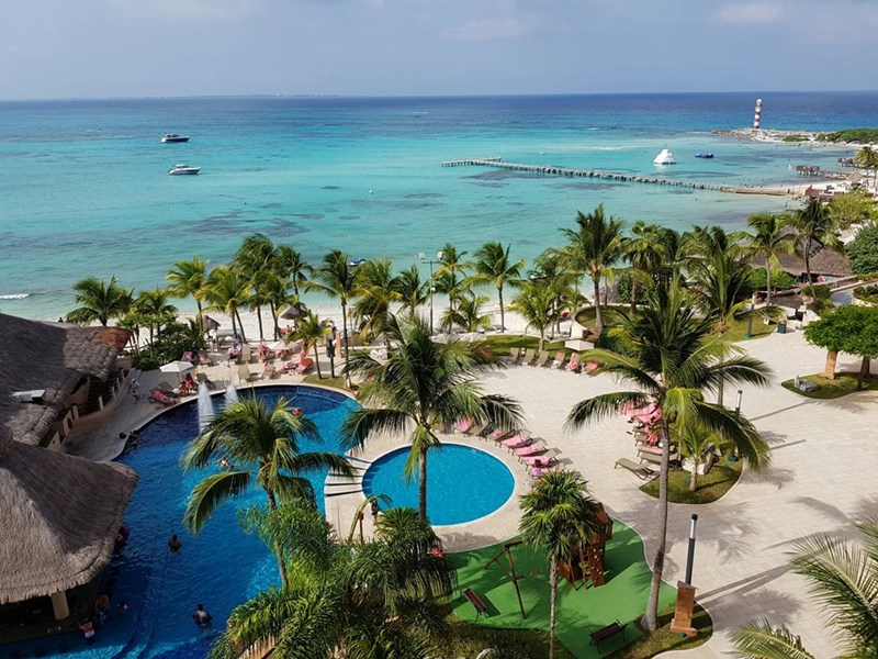 A beachfront all-inclusive resort in Mexico with clear waters, palm trees, pools, and tropical beaches.