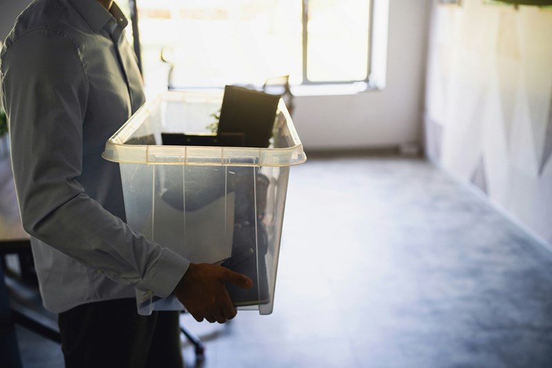 Person carrying a box with their belongings in an office.