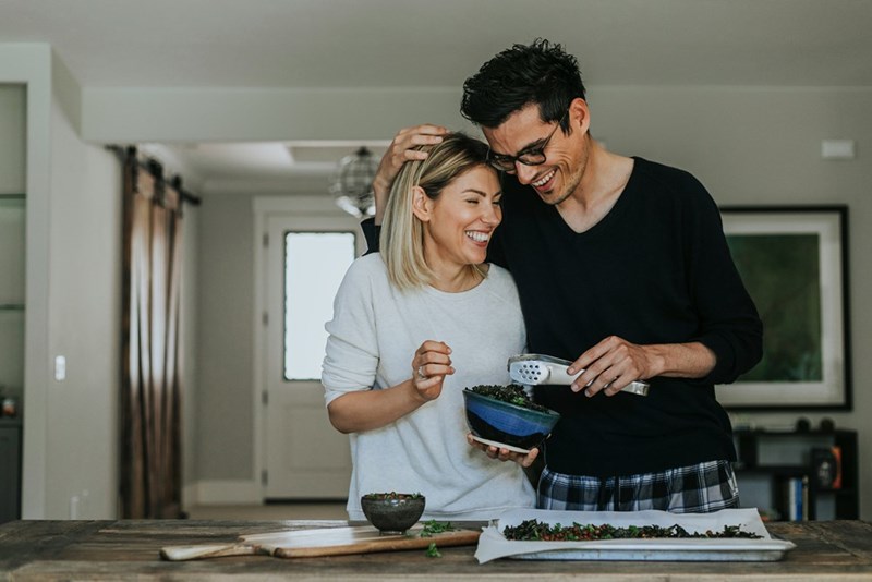 A couple spends time in the kitchen together after a roommate dispute over privacy, personal space, and bathroom boundaries.