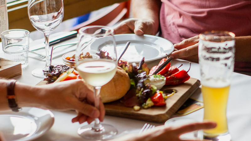 Close-up of a sharing dish and multiple drinks glasses on a restaurant table with a couple sitting at it.