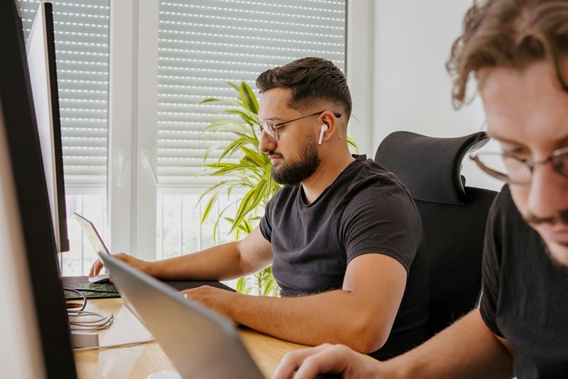 Two men sit next to each other in the workplace