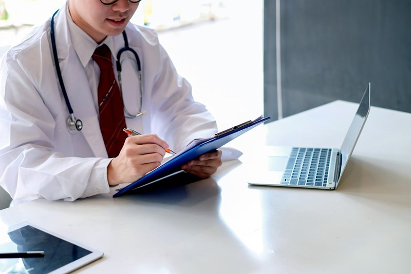 A doctor looking over the files of a 13-year-old boy.