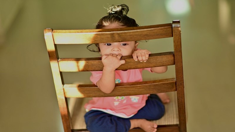 A baby playing in a chair while being babysat. Model portrayal.