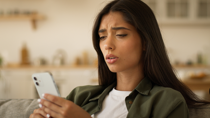 Woman looking at her phone with a disappointed and concered exppraion