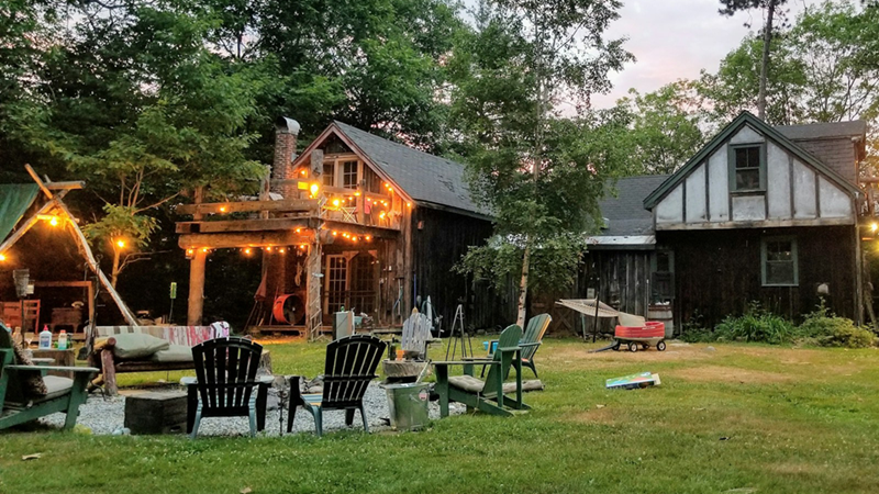 A house with a large backyard and outdoor seating area with fairy lights.