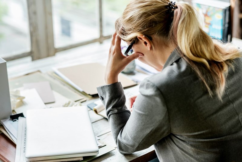A stressed woman looks at documents at her desk