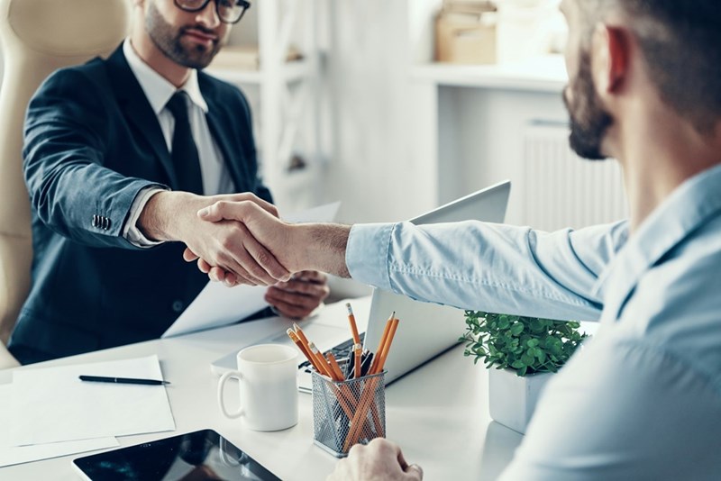 Two men shake hands during a job interview