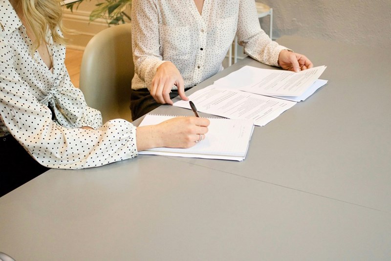 A woman signs documents on a table