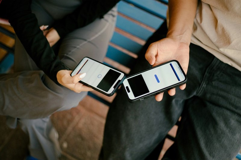 Two people are holding and looking at phones
