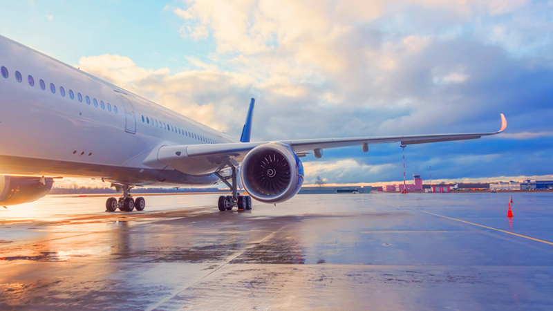 The side of an airplane on the tarmac at an airport.