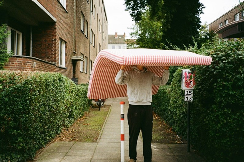 Man carrying a mattress down a sidewalk