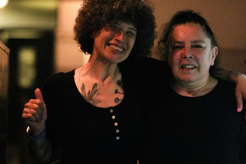 A woman and her mother stand arm in arm
