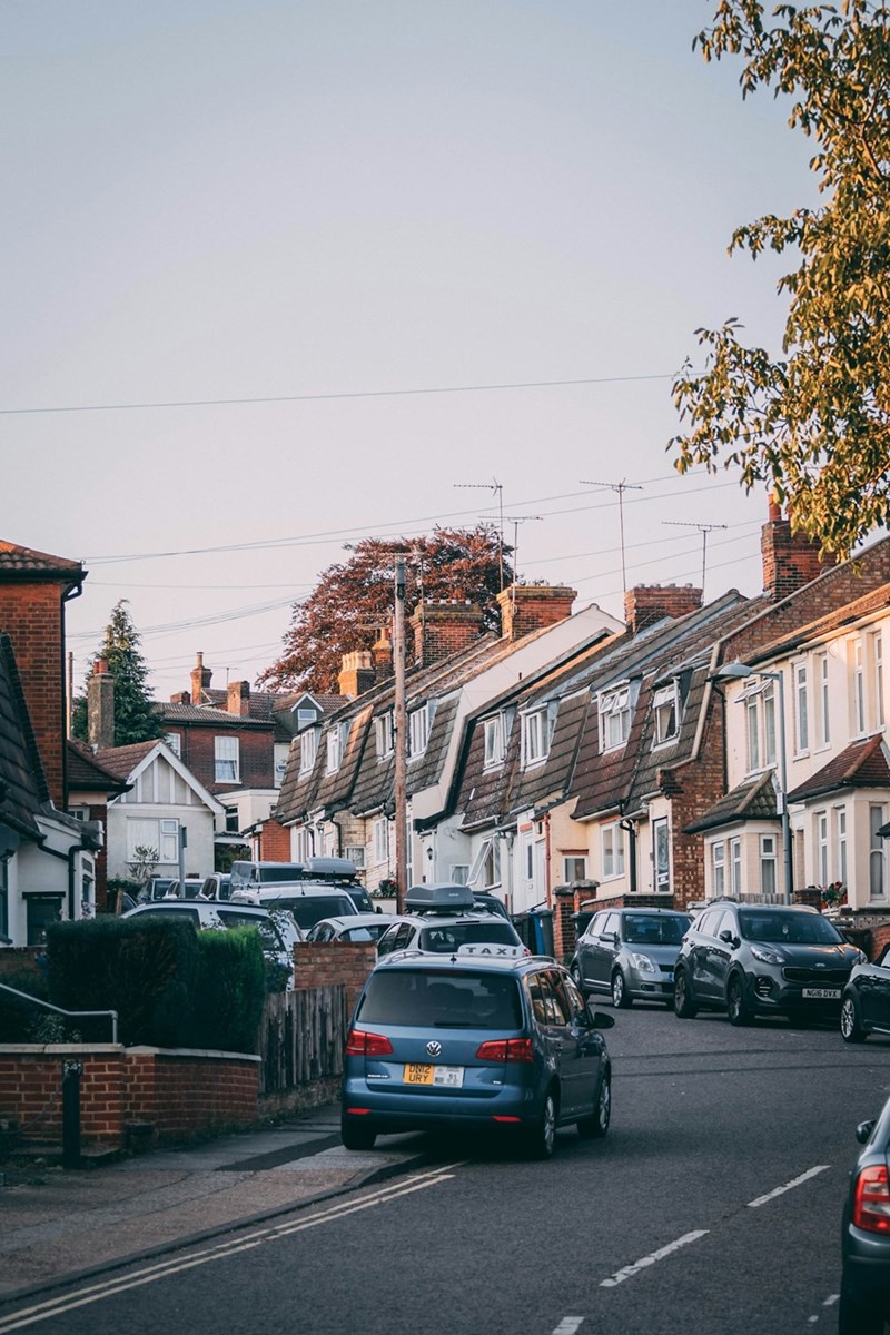 A car parked on a crowded street outside of a row of houses in the UK.