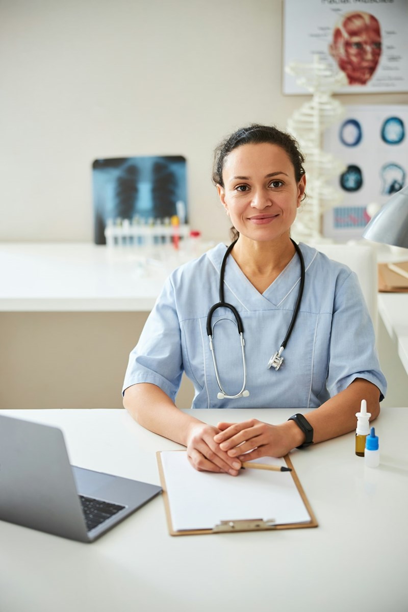 Medical professional bringing her hands together on a notebook and staring ahead of herself