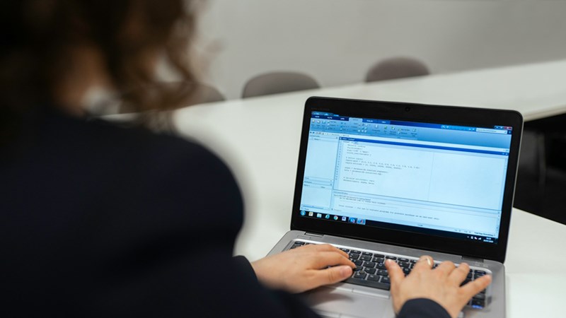 Back view of a person typing on a MacBook.