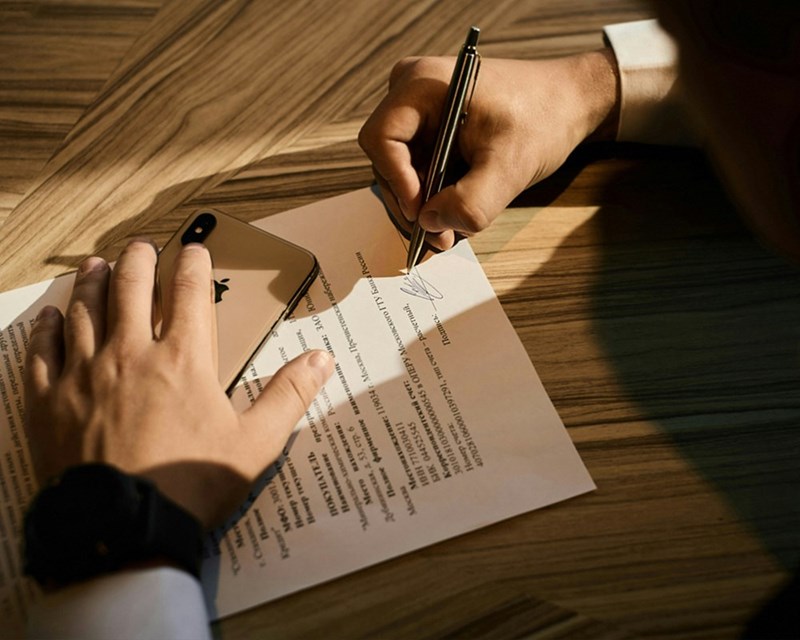 A person writes their signature on a document