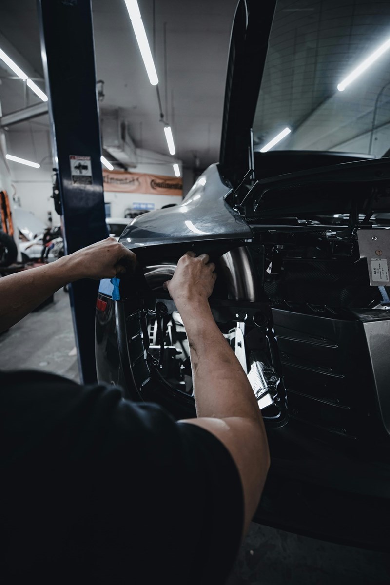 A young car owner works on his vehicle himself to save money on an expensive clutch repair.