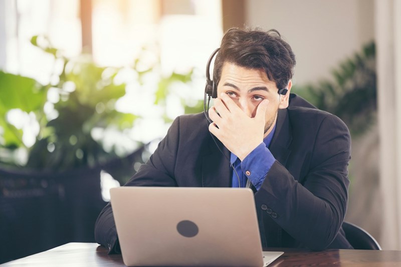 A frustrated businessman with a headset sits at his desk