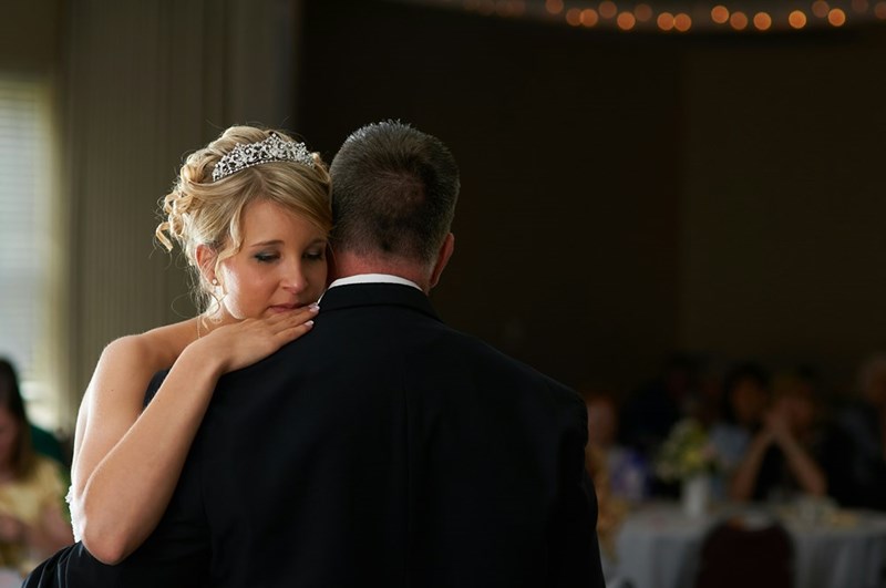 A bride cries on the shoulder of a man at her wedding