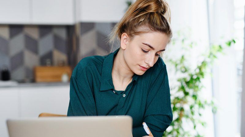 A business owner writing notes in her kitchen.